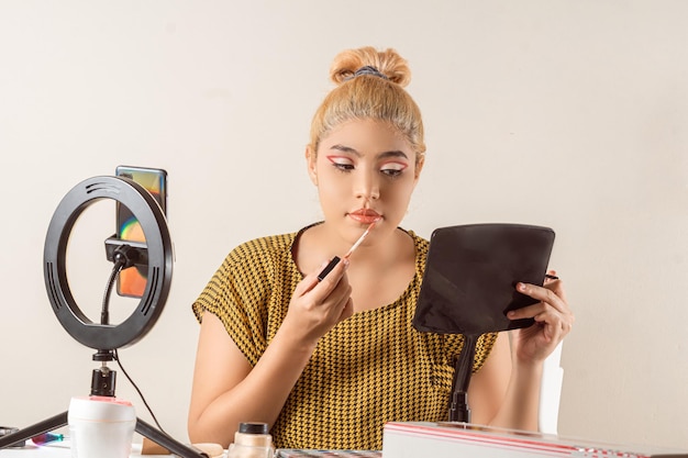 Junge lateinamerikanische Frau, die ein Make-up macht und Live-Videos mit einem Telefon-Influencer-Konzept macht