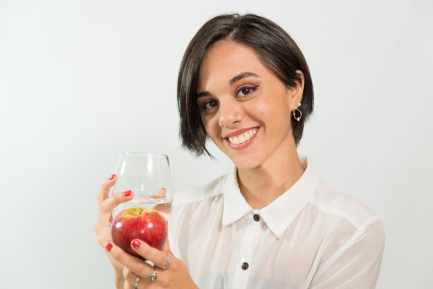 Junge lateinamerikanische Frau, die einen Apfel und ein Glas Wasser in ihren Händen hält