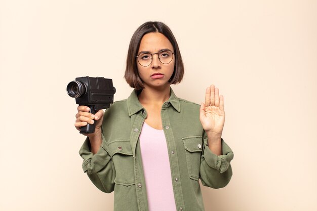 Foto junge lateinamerikanische frau, die ernst, streng, unzufrieden und wütend aussieht und offene handfläche zeigt, die stoppgeste macht