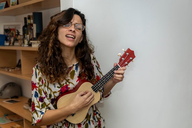 Junge lateinamerikanische Frau singt und spielt Ukulele