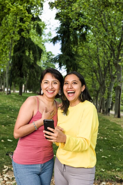 Junge lateinamerikanische Frauen in einem Videoanruf mit einem Smartphone mit Freunden verursachen mithilfe von Technologie eine Konferenz zur sozialen Distanz nach Bolivien in Südamerika