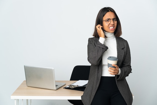 Junge lateinamerikanische Geschäftsfrau, die in einem Büro arbeitet, isoliert auf weißem Hintergrund, frustriert und für die Ohren