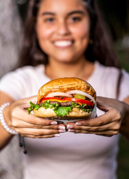 Foto junge lateinamerikanische peruanische frau posiert und genießt mit hamburger und hamburgerbox