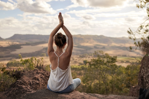 Junge lateinische Frau, die in der Natur meditiert. Gesunde Yogafrauenmeditation bei Sonnenuntergang.