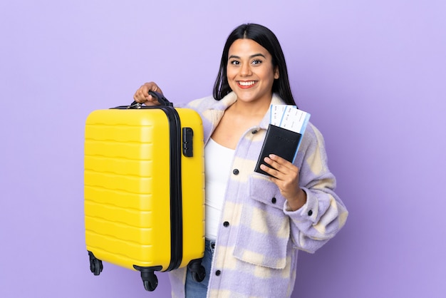 Junge lateinische Frau Frau lokalisiert auf lila im Urlaub mit Koffer und Pass