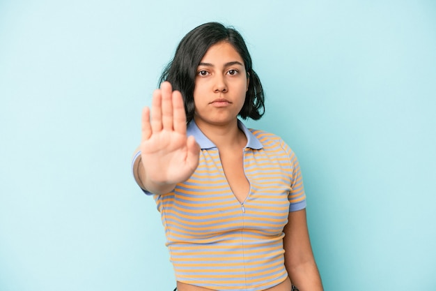 Junge lateinische Frau isoliert auf blauem Hintergrund, die mit ausgestreckter Hand steht und Stoppschild zeigt und Sie verhindert.