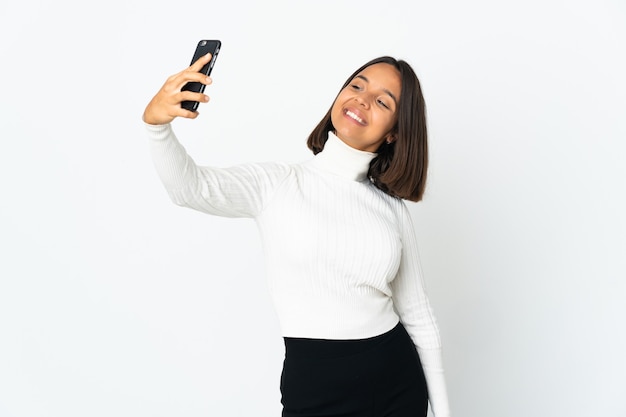 Junge lateinische Frau lokalisiert auf weißem Hintergrund, der ein selfie macht