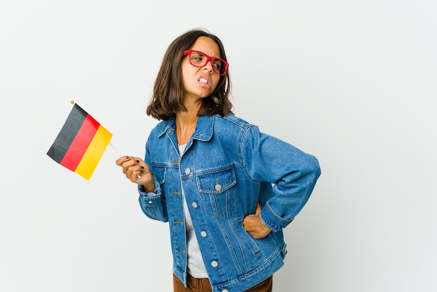 Junge lateinische Frau mit einer deutschen Flagge isoliert auf weißem Hintergrund leidet unter Rückenschmerzen.