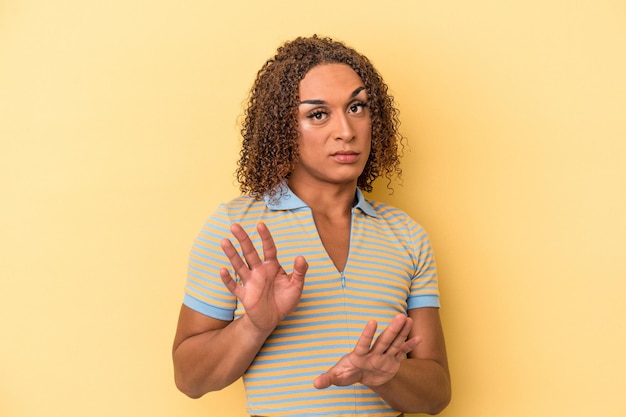 Junge lateinische transsexuelle Frau isoliert auf gelbem Hintergrund, die jemanden ablehnt, der eine Geste des Ekels zeigt.