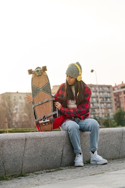 Junge Latina, die mit einem Rucksack sitzt und das Skateboard entfesselt