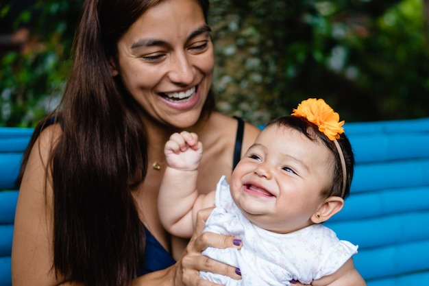 Junge Latina-Mutter mit ihrem lächelnden Baby, das draußen spielt