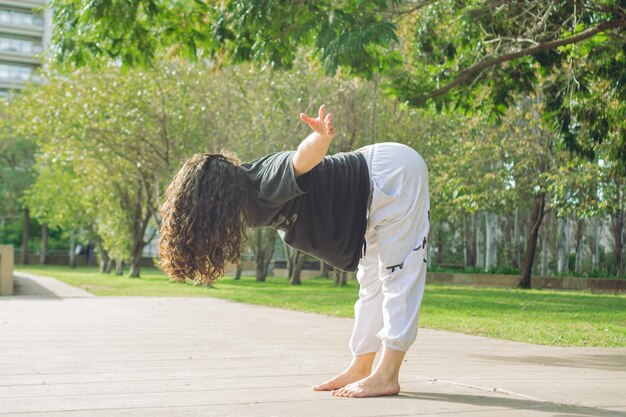 Junge Latina-Tänzerin wärmt sich in einem Stadtpark auf und streckt ihre Beine im Kopierraum aus