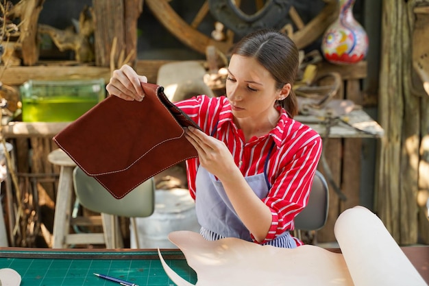 Junge Ledermacherinnen prüfen die Sauberkeit der Ledertasche, bevor sie sie an den Kunden verkaufen