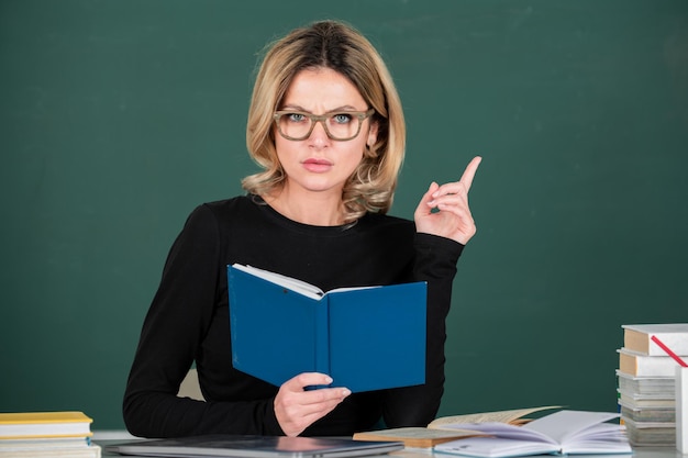 Junge Lehrerin Geschäftsfrau mit Büchern auf Tafel im Klassenzimmer