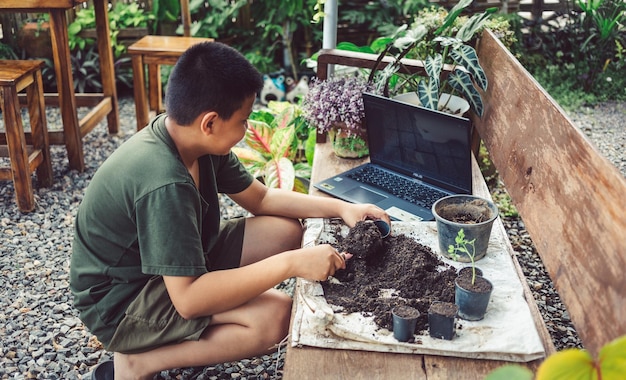 Junge lernt, Blumen in Töpfen anzubauen, indem er online lehrt, Erde in Töpfe zu schaufeln
