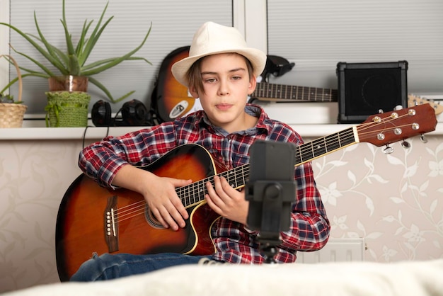 Junge lernt oder hebt den Vlog ab, um über einen Videoanruf Gitarre zu spielen