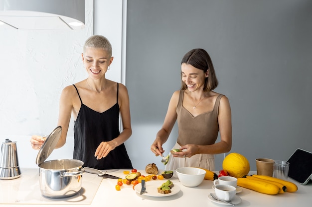 Junge lesbische Paare, die gesundes vegetarisches Essen in der modernen Küche kochen. Gesunde Ernährung, homosexuelle Beziehungen und Lebensstil zu Hause Konzept