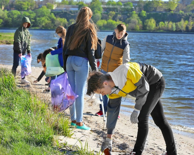 Junge Leute, die den Strandbereich reinigen Freiwilligenarbeitskonzept