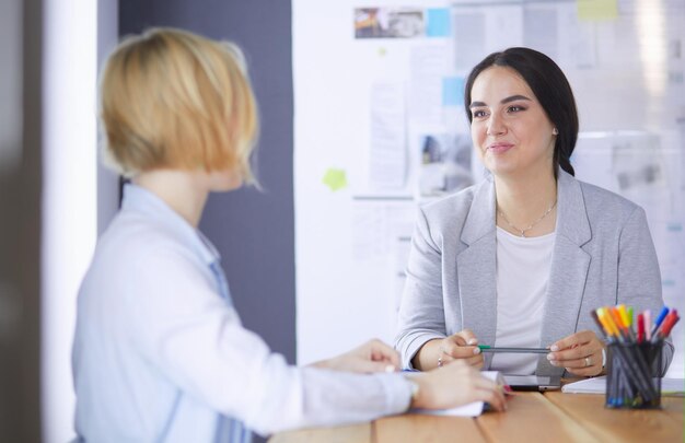 Junge Leute, die mit Büchern auf dem Schreibtisch studieren, schöne Frauen und Männer, die zusammenarbeiten