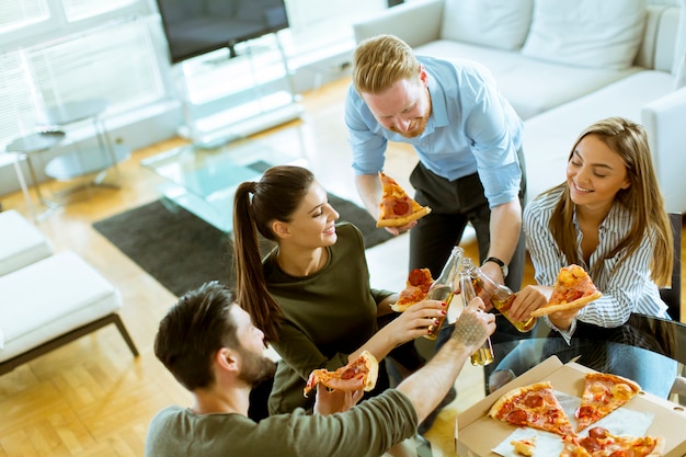 Junge Leute, die Pizza essen und Apfelwein im modernen Innenraum trinken