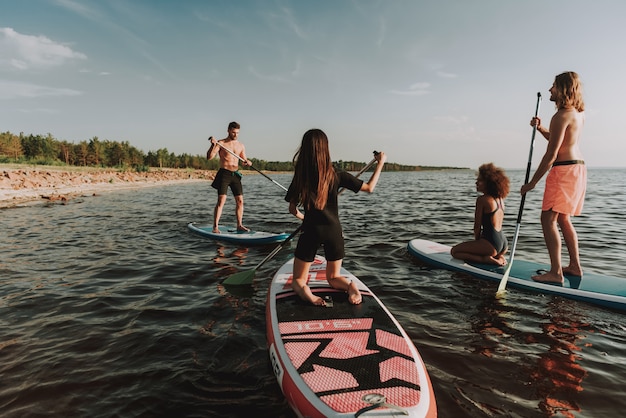 Junge Leute, die Surfs im Meer mit Paddeln rudern.