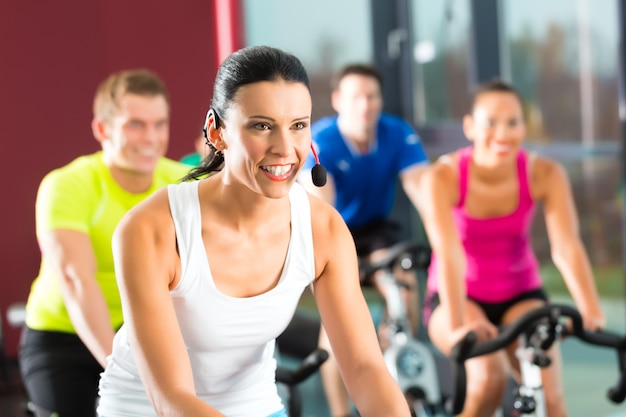 Junge Leute, Frauengruppe und Männer, die den Sport spinnt in die Turnhalle für Eignung tun