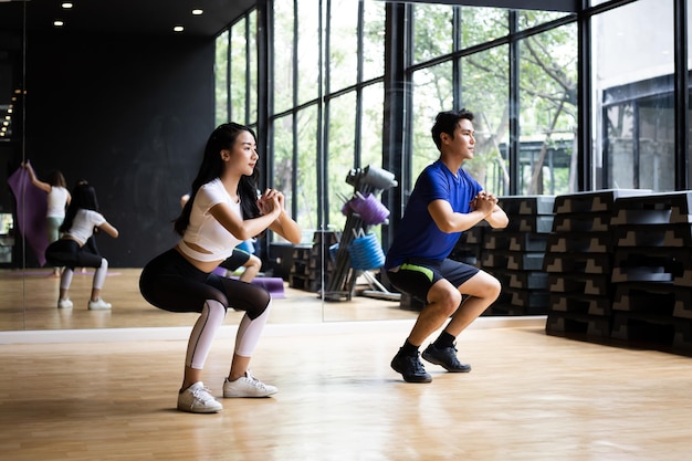 Junge leute machen lange kniebeugen im fitnessstudio mit kraft.