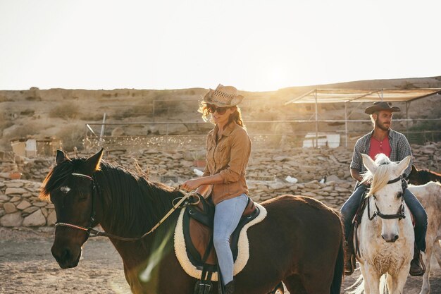 Junge Leute reiten auf Pferden und machen einen Ausflug bei Sonnenuntergang. Konzentrieren Sie sich auf die Hand einer Frau