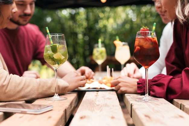 Junge Leute sitzen am Restauranttisch mit Cocktails und Essen