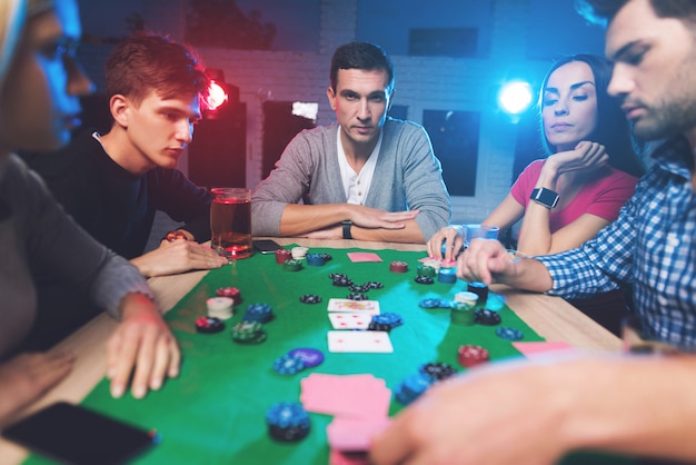 Junge Leute spielen Poker am Tisch.