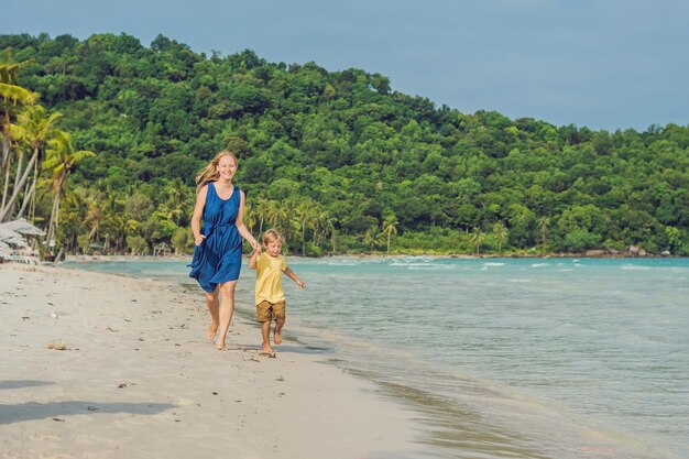 Junge liebevolle Mutter und ihr kleiner Sohn spielen am Strand