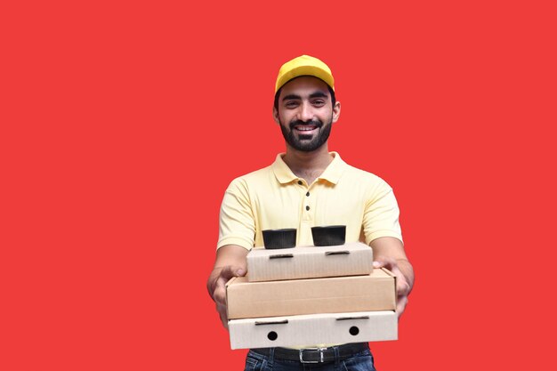 Junge Lieferbote Frontlook in gelbem T-Shirt und Mütze mit 3 Pizzakartons indisches pakistanisches Modell