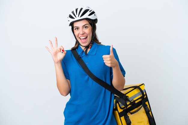 Junge Lieferfrau mit Thermorucksack isoliert auf weißem Hintergrund mit OK-Zeichen und Daumen-hoch-Geste