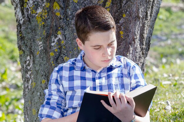 Junge liest ein Buch im Wald mit geringer Schärfentiefe und Kopierraum