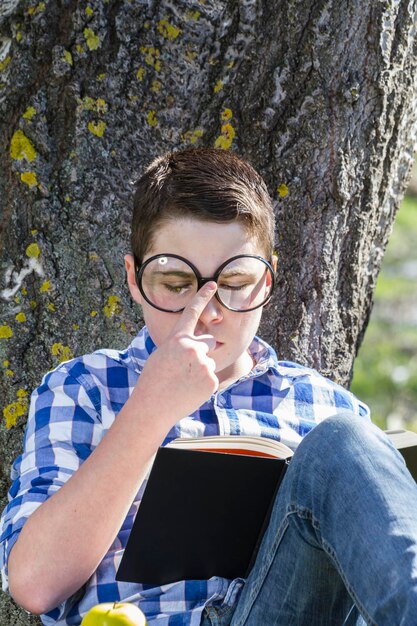 Junge liest ein Buch im Wald mit geringer Schärfentiefe und Kopierraum
