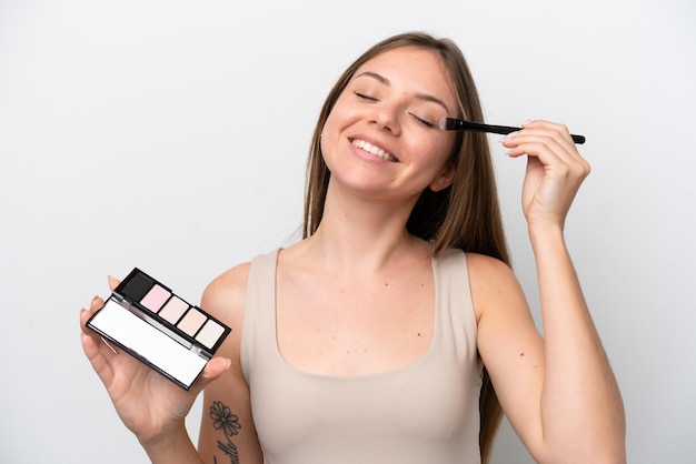 Junge Litauerin isoliert auf weißem Hintergrund mit Make-up-Palette und glücklich