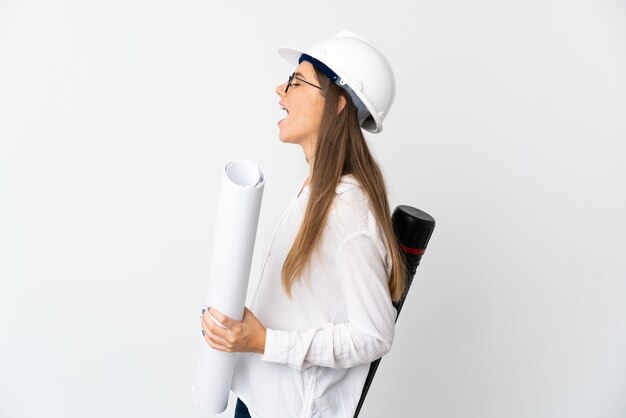 Junge litauische Architektenfrau mit Helm und Halteplänen lokalisiert auf weißem Hintergrund lachend in seitlicher Position