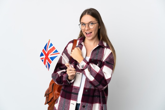 Junge litauische Frau, die eine britische Flagge lokalisiert auf weißer Wand hält, die einen Sieg feiert