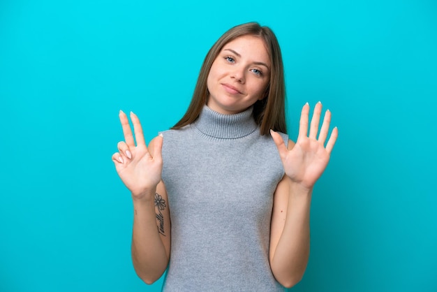 Junge litauische Frau isoliert auf blauem Hintergrund, die acht mit den Fingern zählt