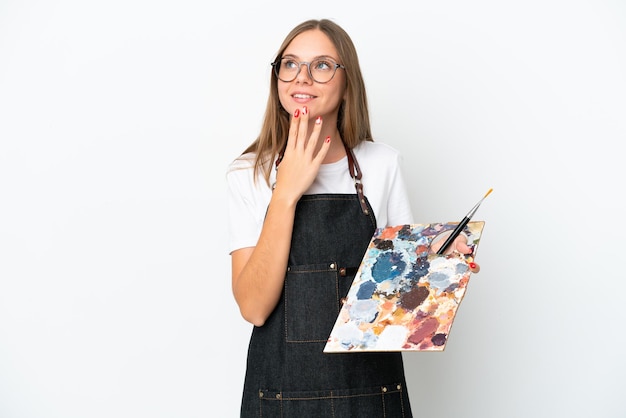 Junge litauische Künstlerin, die eine Palette isoliert auf weißem Hintergrund hält und lächelnd aufblickt