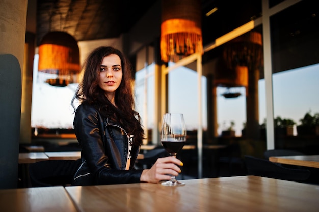 Junge lockige Frau, die ihren Wein in einer Bar genießt