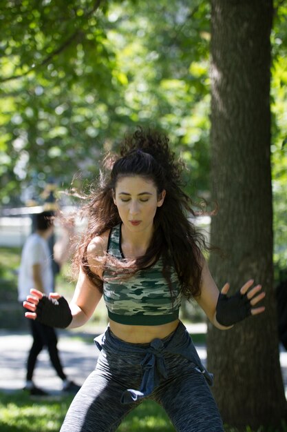 Junge lockige Frau, die im Sommerpark Situps macht