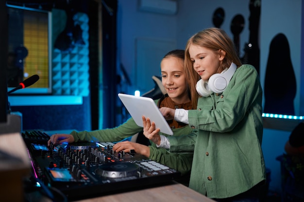 Junge Mädchen, die Musik mit digitaler Tablet-Software und Sound-Mixer-Konsole im Radiosender oder Plattenstudio machen