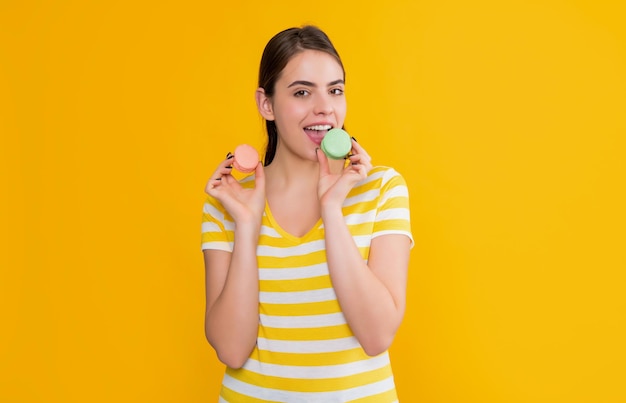 Junge Mädchen essen Macaron auf gelbem Hintergrund