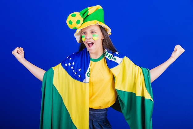 Junge Mädchen Fußballfan aus Brasilien gekleidet in Hut und Flagge feiern