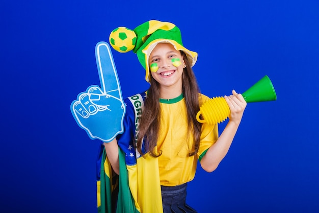 Junge Mädchen Fußballfan aus Brasilien gekleidet in Hut und Flagge mit Schaumfinger
