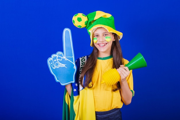 Junge Mädchen Fußballfan aus Brasilien gekleidet in Hut und Flagge mit Schaumfinger