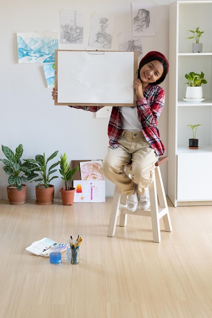 Junge Mädchen halten Rahmen und Papier zu Hause Hobby- und Kunststudium zu Hause