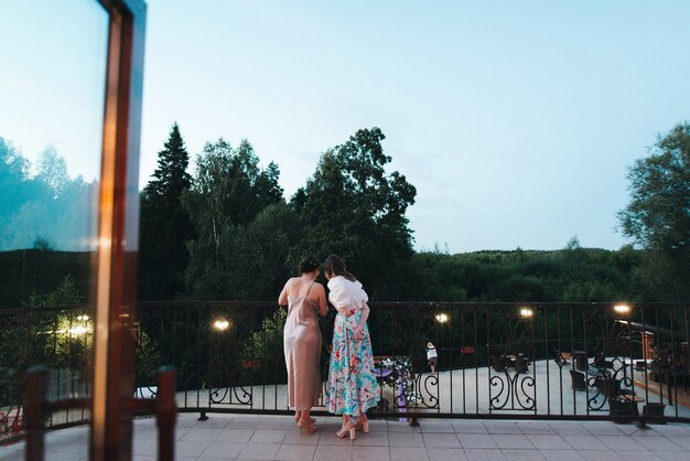 Foto junge mädchen in schönen kleidern stehen auf dem balkon im restaurant