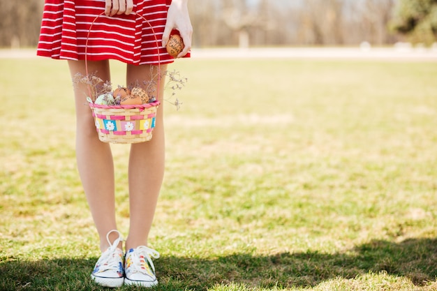 Junge Mädchenbeine und Korb mit gemalten Ostereiern im Freien